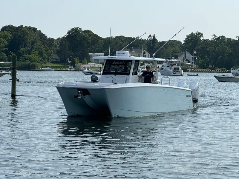 Slide: The Image of 2025 Twin Vee 400 GFX boat cruising on a calm lake with trees in the background. - 26