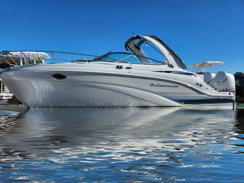 Slide: The Image of 2024 Crownline 280 CRX boat on calm water under clear blue sky. - 0