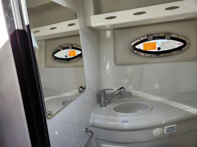 Slide: The Image of 2024 Crownline 280 CRX boat bathroom with sink, mirror, and porthole window. - 11
