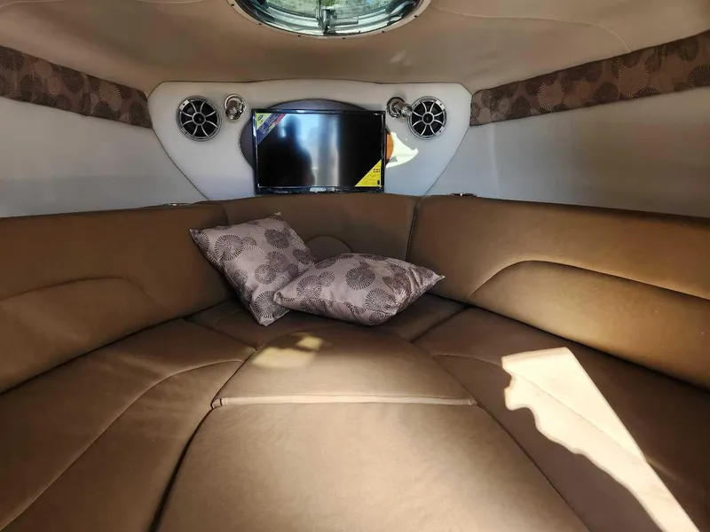 Slide: The Image of 2024 Crownline 280 CRX cabin interior with brown seating, pillows, and TV. - 7