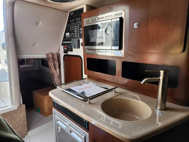 Slide: The Image of 2024 Crownline 280 CRX boat interior with kitchenette, microwave, sink, and control panel. - 8