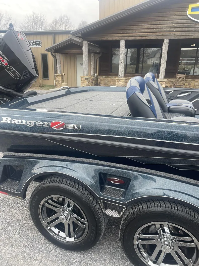 Slide: The Image of 2021 Ranger Z521L boat with dual seats and trailer, parked outside a building. - 2