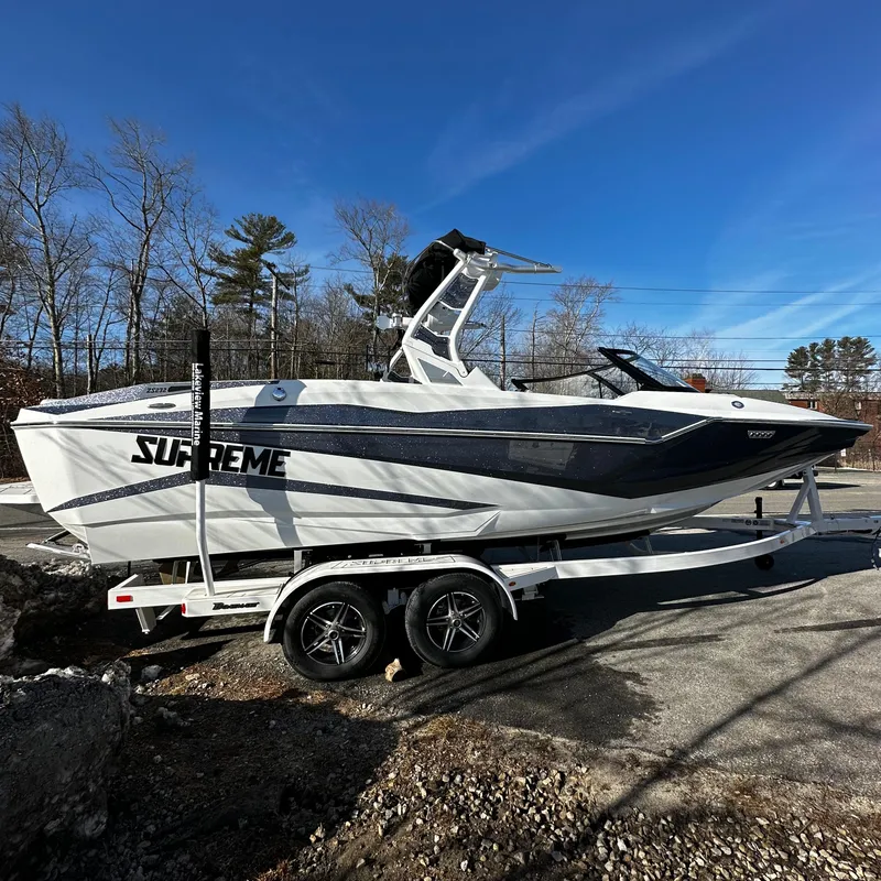Slide: The Image of 2023 Supreme ZS232 boat on a trailer, parked outdoors on a sunny day. - 2