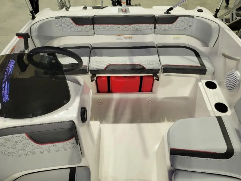 Slide: The Image of 2024 Bayliner M15 boat interior with gray and red seating, steering wheel, and cup holders. - 5