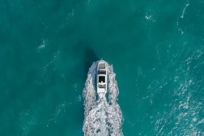 Slide: The Image of 2024 Sea Ray Sundancer 320 Outboard cruising on turquoise water, aerial view. - 2