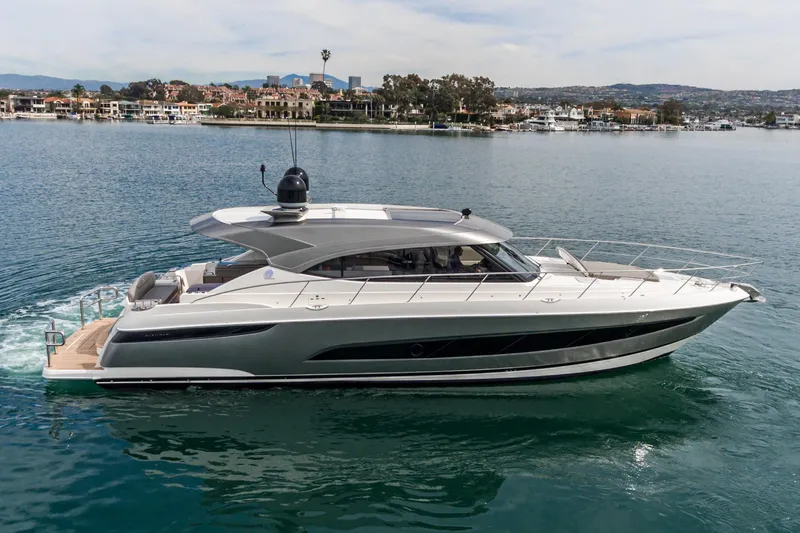 Slide: The Image of 2020 Riviera 5400 Sport Yacht cruising on a calm waterfront with scenic background. - 1