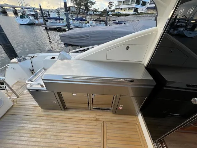 Slide: The Image of Outdoor kitchen on 2020 Riviera 5400 Sport Yacht, featuring stainless steel appliances and wooden deck. - 20