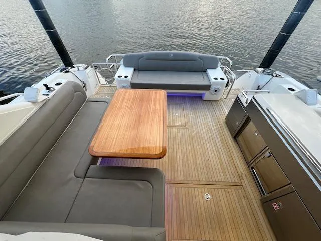 Slide: The Image of Luxurious 2020 Riviera 5400 Sport Yacht deck with seating and wooden table. - 25