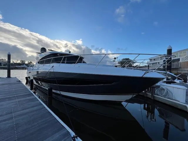 Slide: The Image of 2020 Riviera 5400 Sport Yacht docked at marina under a partly cloudy sky. - 5