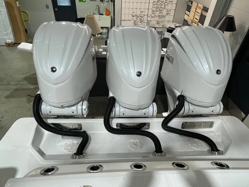 Slide: The Image of 2023 Robalo R360 Center Console with triple outboard engines in a showroom. - 11