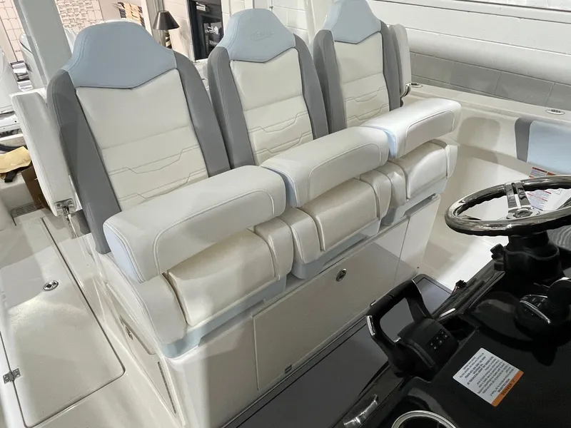 Slide: The Image of 2023 Robalo R360 Center Console boat interior with three cushioned seats and steering wheel. - 3