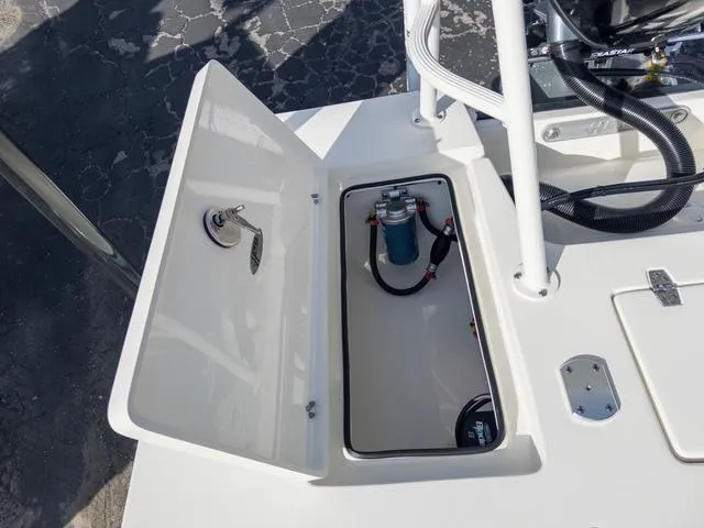 Slide: The Image of 2024 Hewes Redfisher 18 boat storage compartment with open hatch and visible equipment. - 14