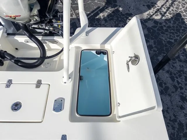 Slide: The Image of 2024 Hewes Redfisher 18 boat storage compartment with open hatch and key lock. - 15