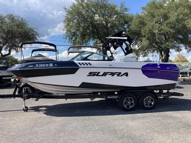 The Image of 2016 Supra SA 400 boat on trailer, white and purple, parked outdoors. - 1