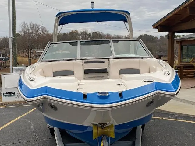 Slide: The Image of 2018 Chaparral 224 Sunesta boat with blue and white exterior, docked on a trailer. - 4
