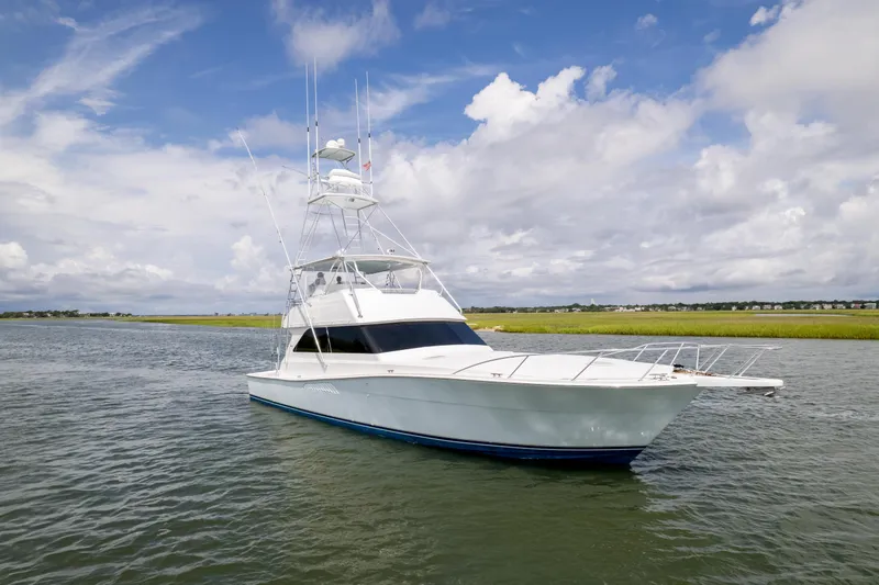 Slide: The Image of 1999 Viking 58 Convertible yacht on calm waters under a partly cloudy sky. - 4