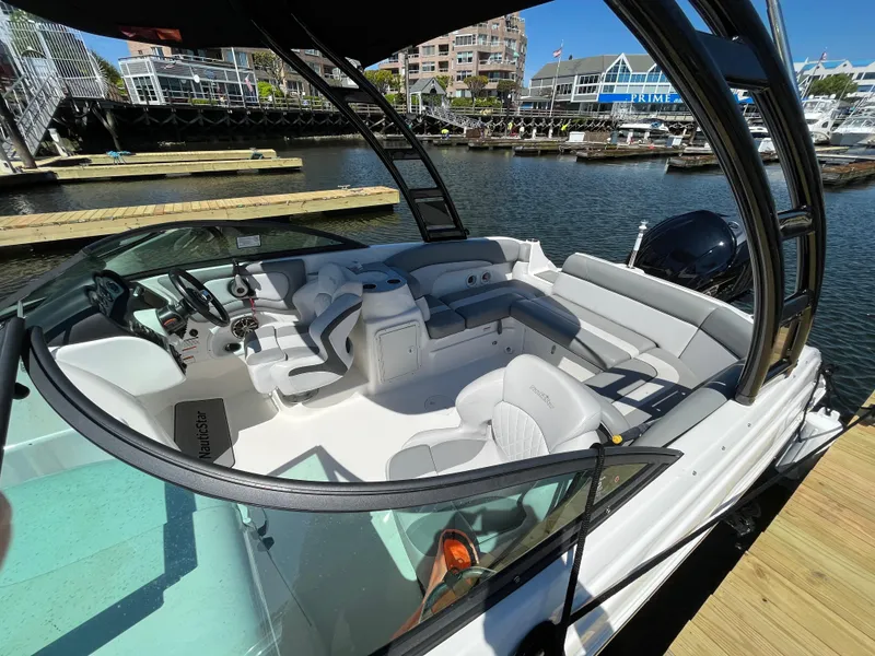 Slide: The Image of 2021 NauticStar 243DC Sport Deck boat docked at marina, featuring spacious seating. - 7