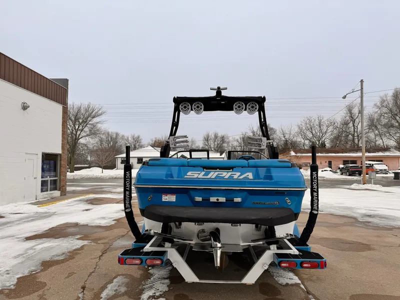 Slide: The Image of 2021 Supra SR boat in blue, rear view, parked outdoors in winter. - 3