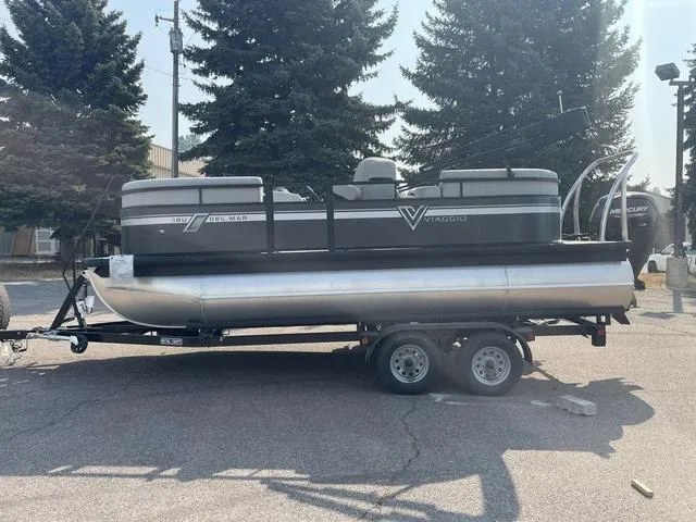 Slide: The Image of 2023 Viaggio DM18U pontoon boat on a trailer, parked outdoors. - 7