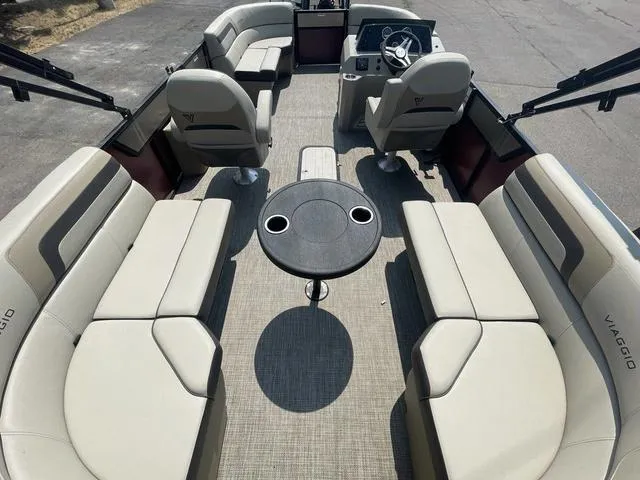 Slide: The Image of 2023 Viaggio l20u pontoon boat interior with beige seating and central table. - 12