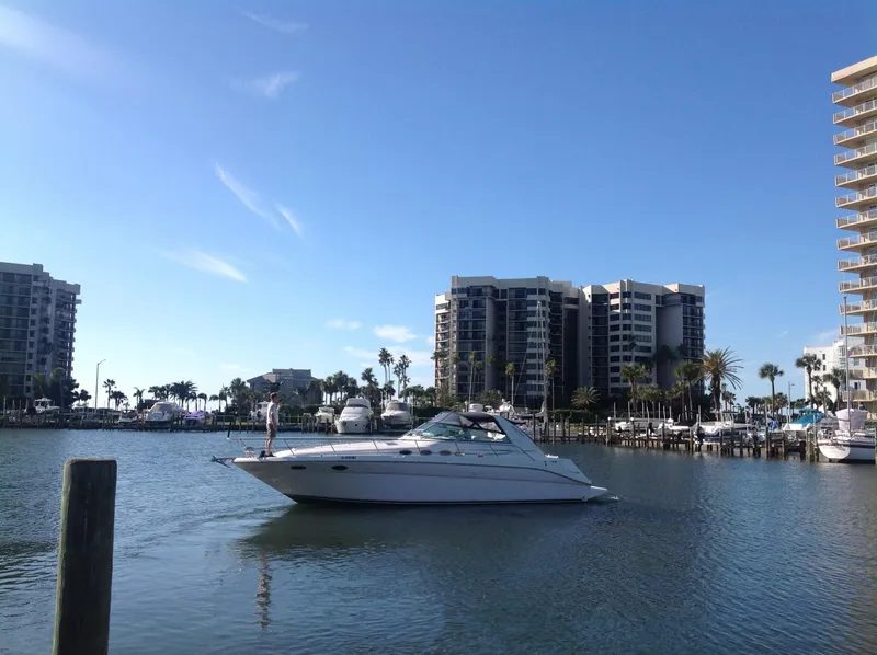 The Image of 1995 Sea Ray 370 Sundancer yacht cruising in a marina with high-rise buildings in the background. - 0