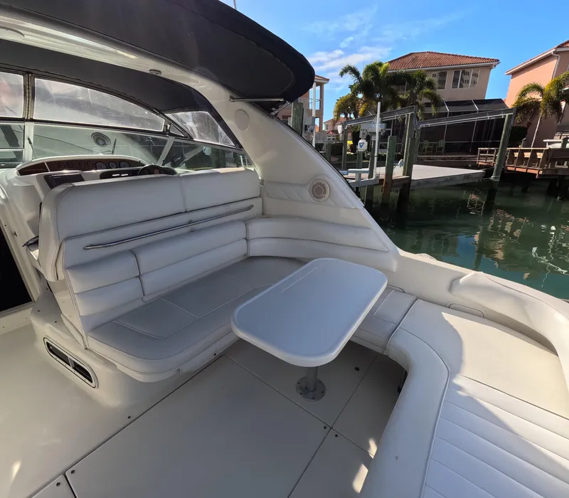 Slide: The Image of 1995 Sea Ray 370 Sundancer boat interior with white seating and table, docked near waterfront homes. - 45