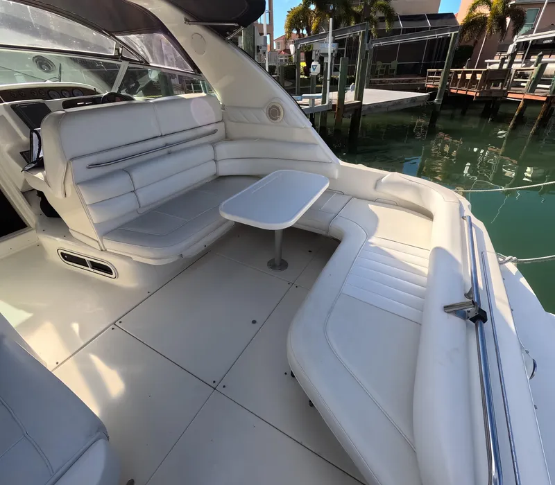 Slide: The Image of 1995 Sea Ray 370 Sundancer boat interior with white seating and table, docked by the water. - 46