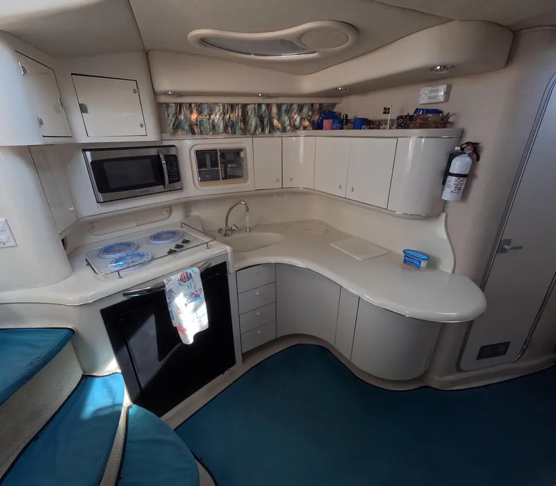 Slide: The Image of 1995 Sea Ray 370 Sundancer kitchen with microwave, stove, sink, and storage cabinets. - 7