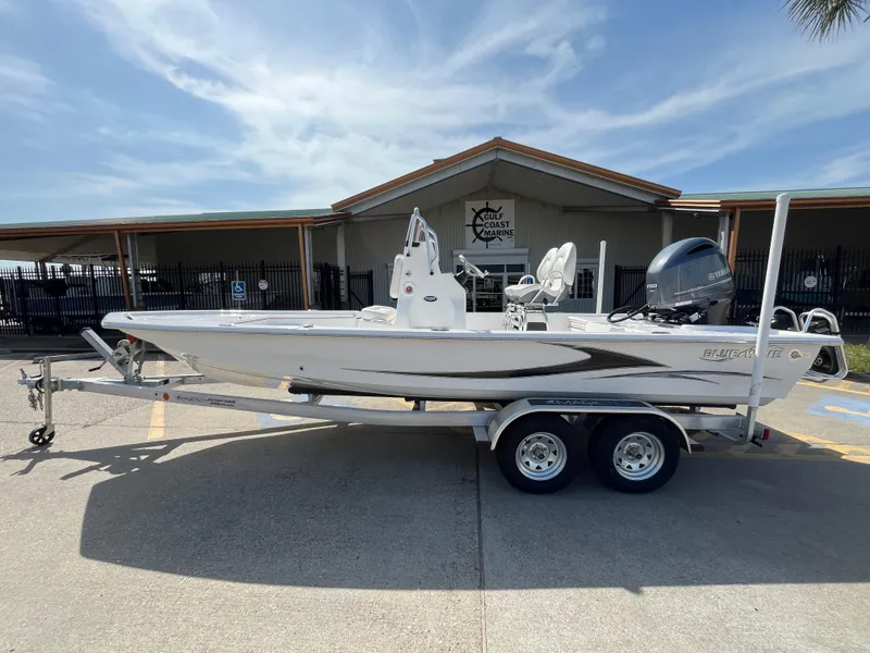 Slide: The Image of 2023 Blue Wave 2200 STL boat on a trailer in front of a building. - 0