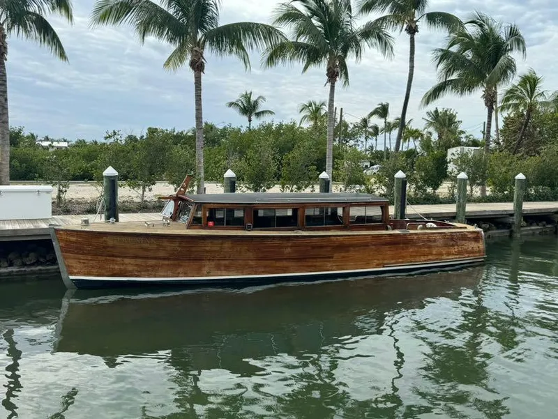 The Image of Classic 1994 Grand Craft 37 wooden boat docked by palm trees. - 0