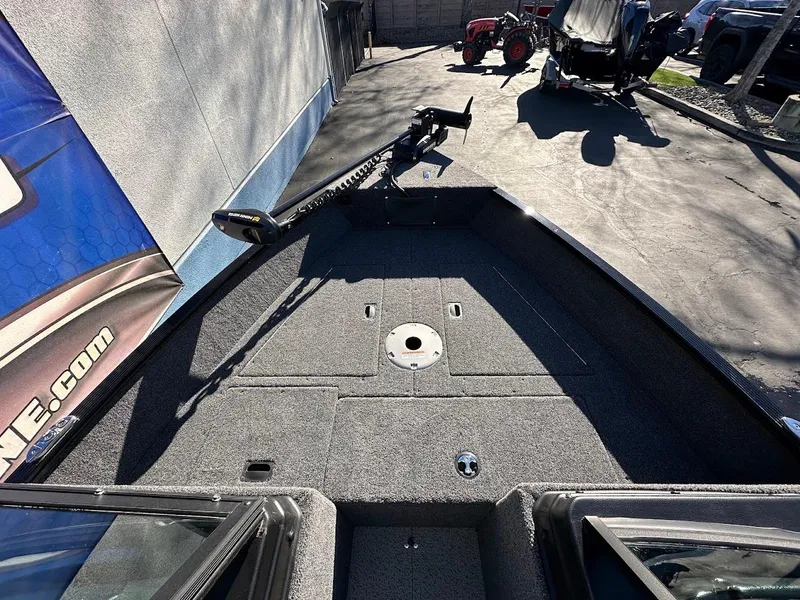 Slide: The Image of 2024 Lund 1650 Angler Sport boat interior with trolling motor, parked outdoors. - 20
