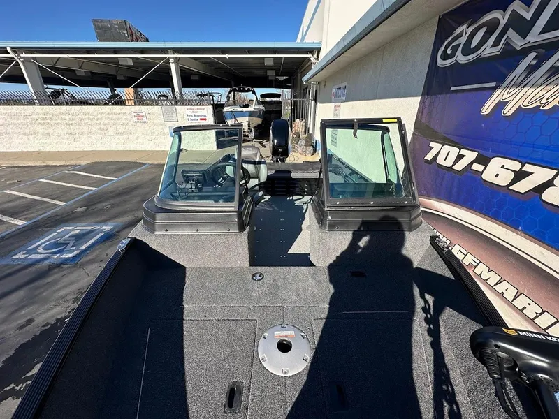 Slide: The Image of 2024 Lund 1650 Angler Sport boat with dual windshields in a parking lot. - 24