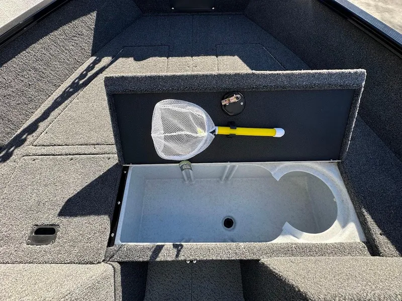 Slide: The Image of 2024 Lund 1650 Angler Sport boat storage compartment with fishing net and tackle. - 27