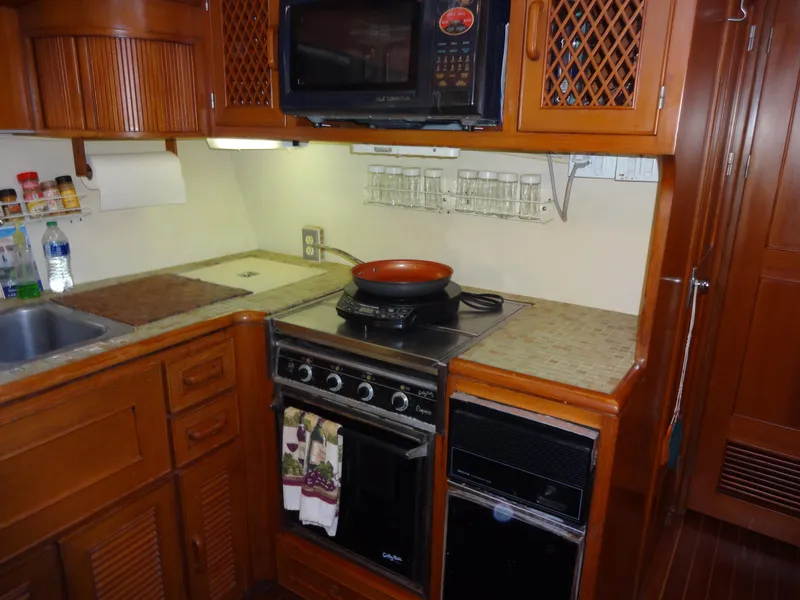 Slide: The Image of 1989 Hi-Star AFT CABIN yacht kitchen with stove, microwave, and wooden cabinetry. - 25