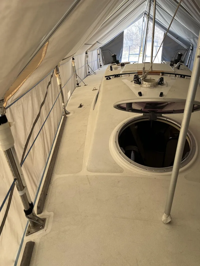 Slide: The Image of 2007 Custom Hallett 33 boat under protective cover, showing deck and open hatch. - 22