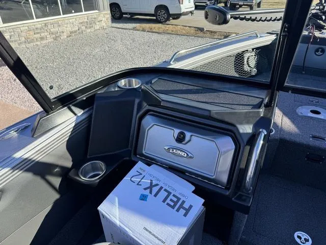 Slide: The Image of 2024 Lund 1975 Tyee Sport boat interior with Helix 7 box, cup holders, and storage compartment. - 12