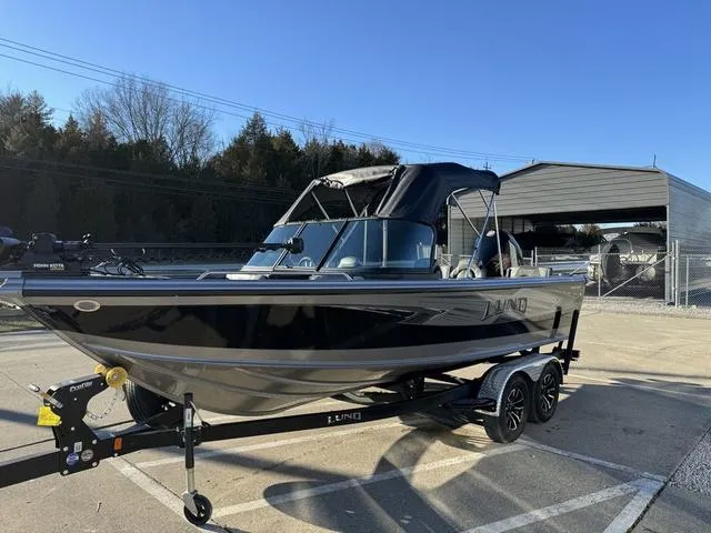 Slide: The Image of 2024 Lund 1975 Tyee Sport boat on trailer in sunny outdoor setting. - 17