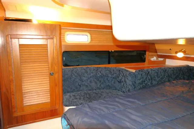 Slide: The Image of Interior cabin of a 1997 Catalina 380 sailboat with wood paneling and cozy bedding. - 16