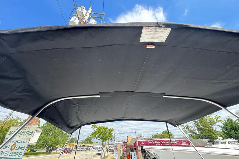 Slide: The Image of 2024 Tidewater 180 CC boat with black canopy, street view in background. - 17