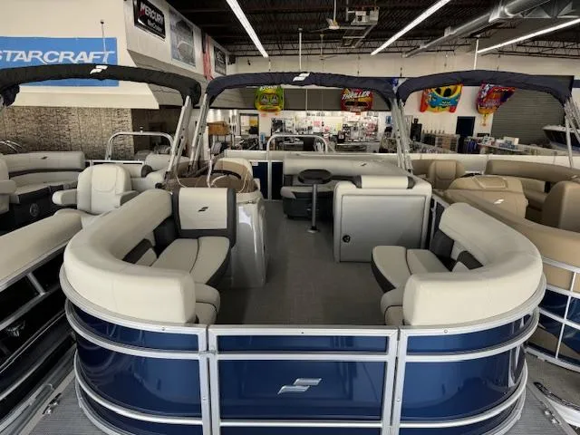 Slide: The Image of 2024 Starcraft EX 20 C pontoon boat with spacious seating in showroom. - 5