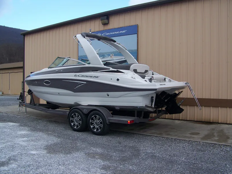 Slide: The Image of 2024 Crownline 260 boat on a trailer outside a beige building. - 3