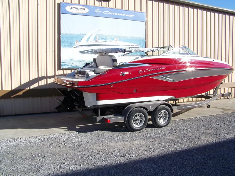 Slide: The Image of 2024 Crownline E235 boat on a trailer, red and white exterior, parked outside. - 4