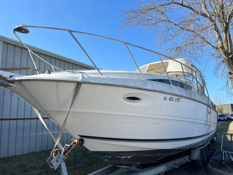 Slide: The Image of 1999 Bayliner 3055 Ciera boat on trailer, parked outdoors near a building and tree. - 10
