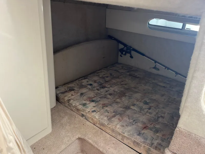 Slide: The Image of 1999 Bayliner 3055 Ciera cabin interior with bed and fishing rods. - 2