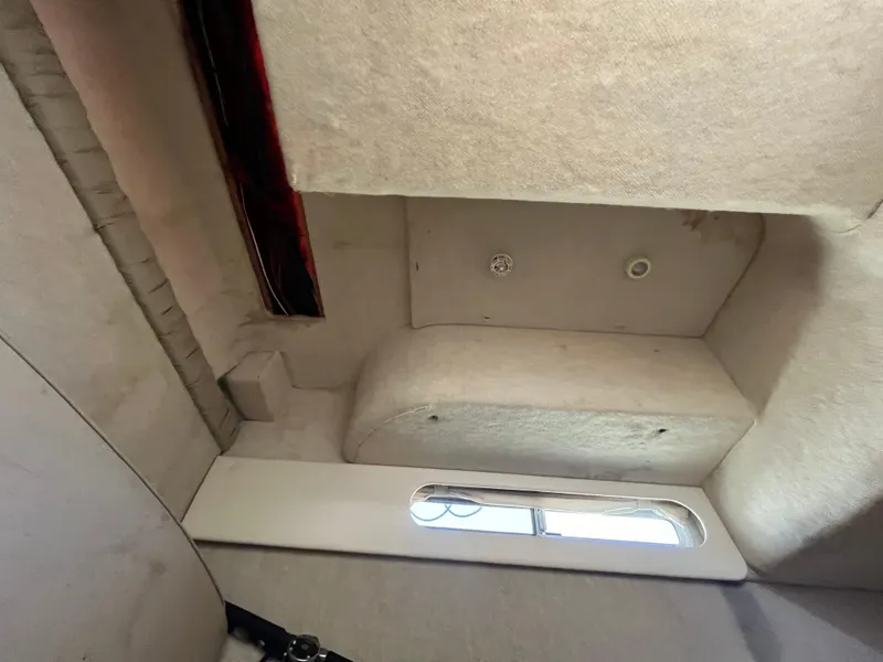 Slide: The Image of Interior cabin view of a 1999 Bayliner 3055 Ciera boat, featuring a window and beige upholstery. - 3