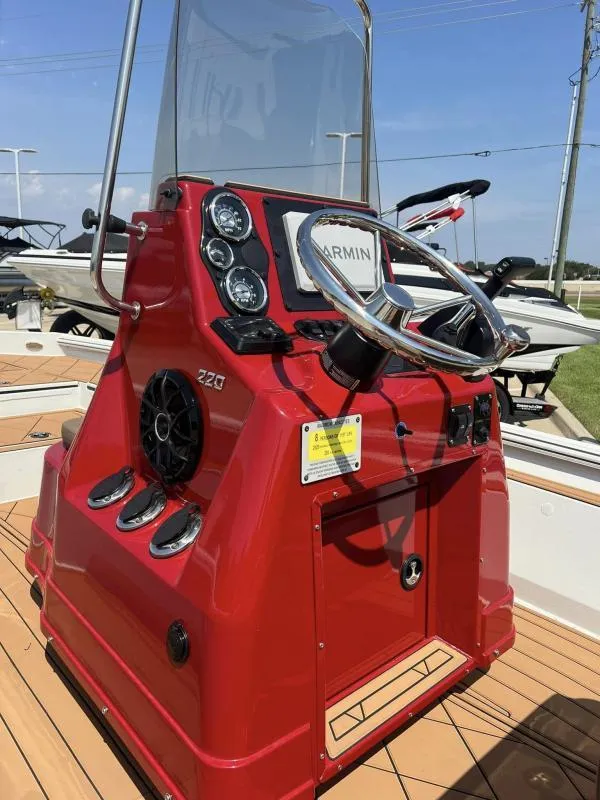 Slide: The Image of 2023 Excel Boats 220 Bay Pro, red console with steering wheel and gauges. - 9