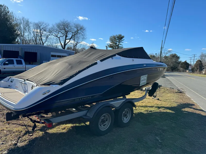 Slide: The Image of 2017 Yamaha Boats 212 Limited on trailer, covered, parked roadside. - 3