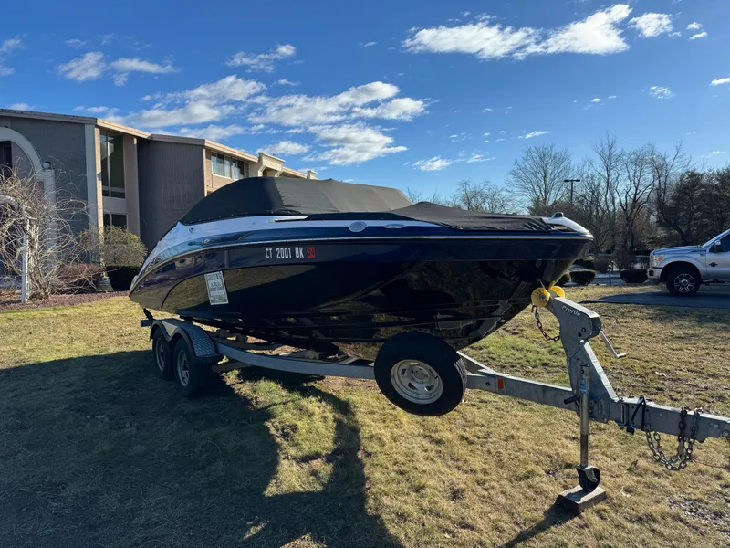 Slide: The Image of 2017 Yamaha Boats 212 Limited on trailer, parked on grass, with cover on. - 5