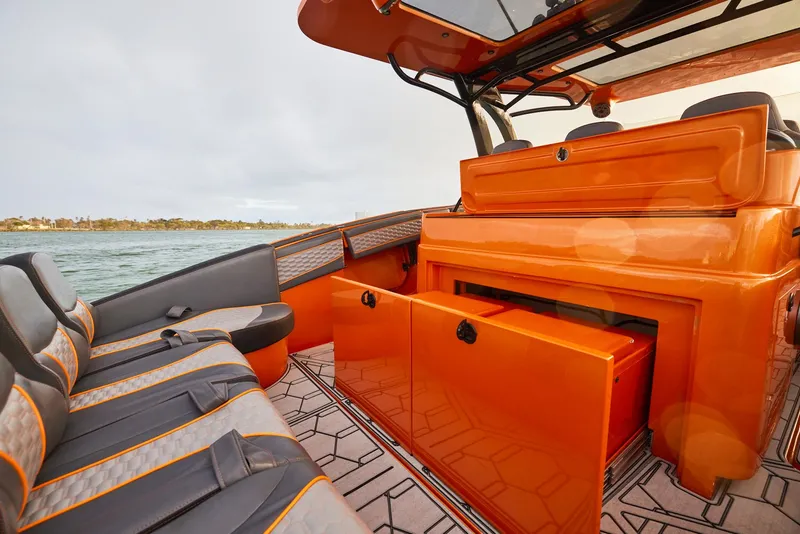 Slide: The Image of 2023 Midnight Express 43' Solstice boat interior with orange and gray seating, open storage. - 16