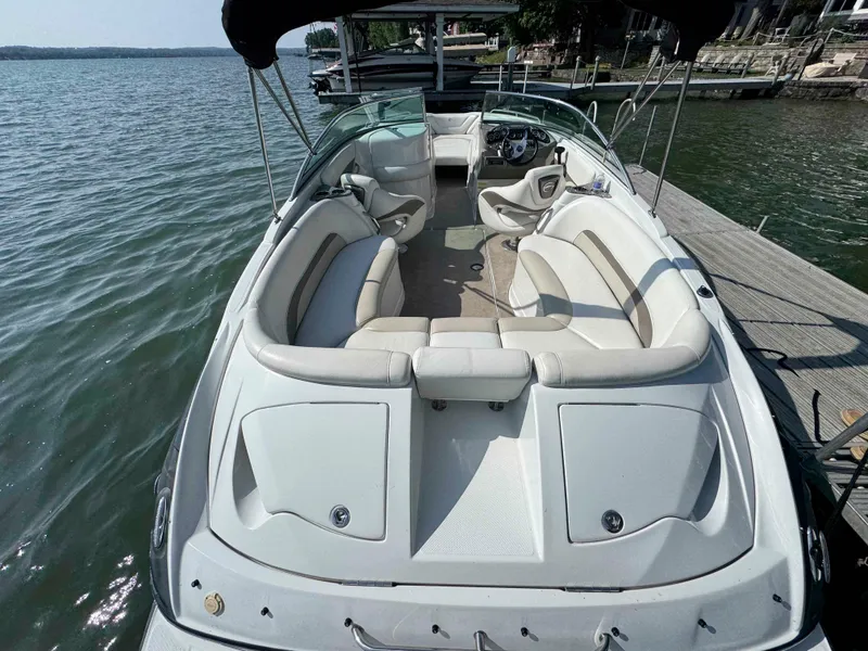 Slide: The Image of 2010 Crownline 240 LS boat with spacious seating, docked by a serene lake. - 4